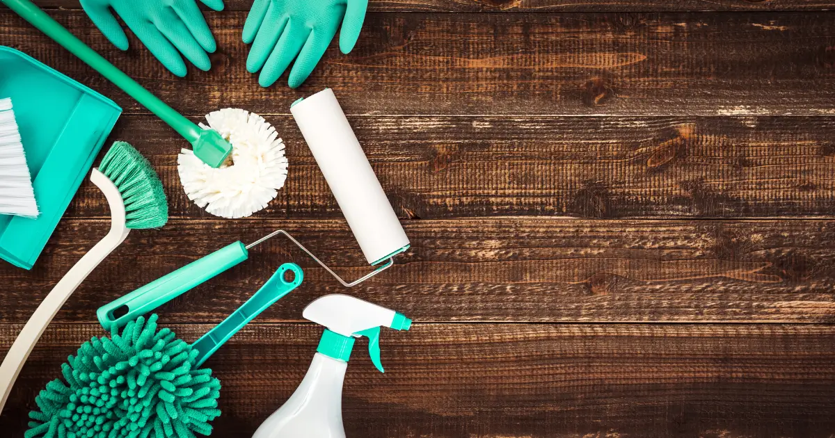 Assorted cleaning supplies on a wooden surface, representing seasonal deep cleaning tips to refresh your living space.