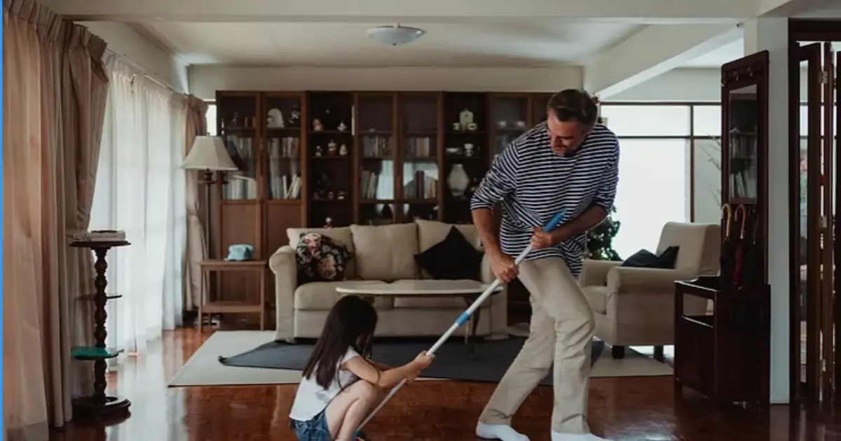 A father and daughter cleaning the living room together as part of quick and easy move-out cleaning hacks. Caption: Cleaning together makes pre-move tasks faster and more manageable.