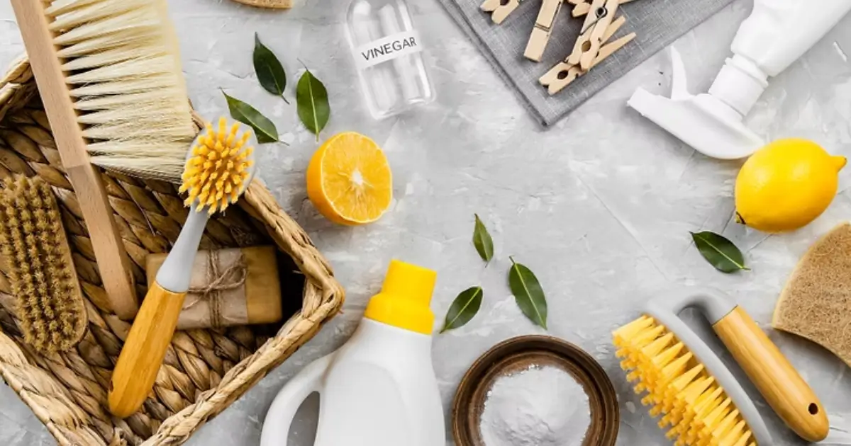 Eco-friendly cleaning tools and natural ingredients like lemon, vinegar, and baking soda arranged on a countertop.