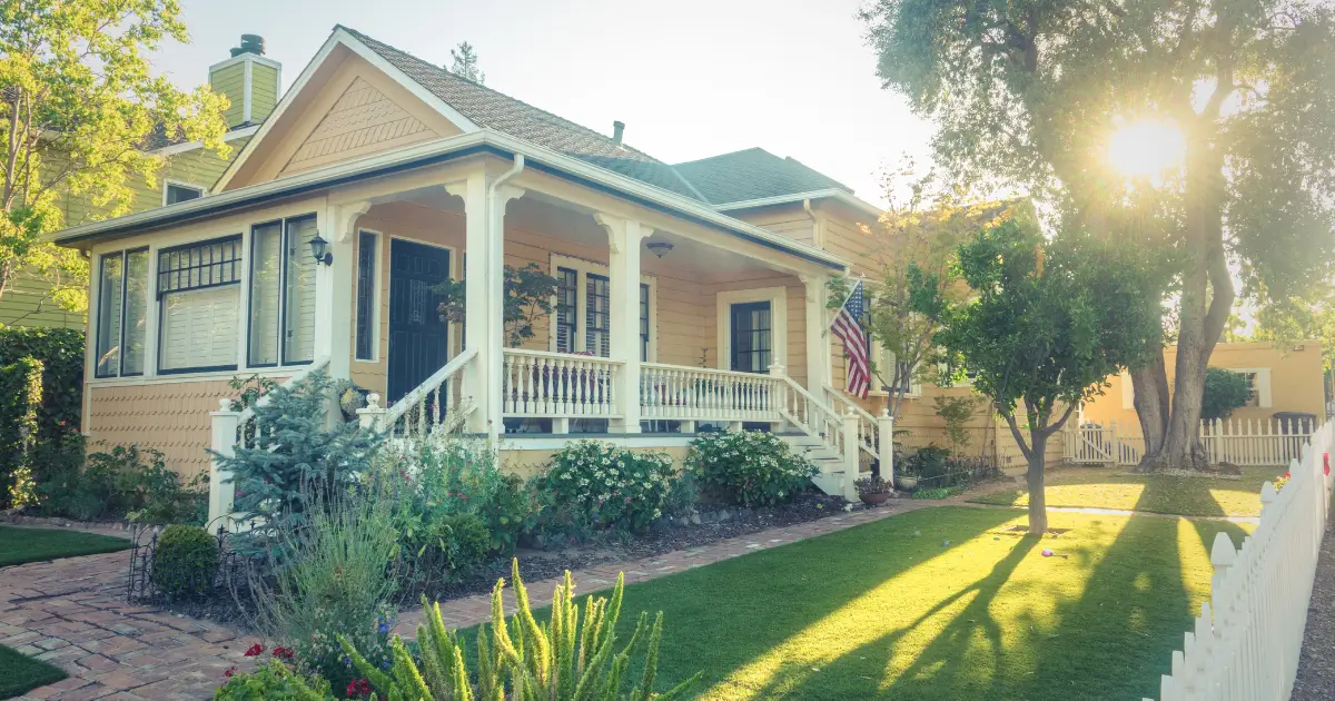 Well-maintained home exterior with sunlight, green lawn, and trees representing a fresh and clean home during spring